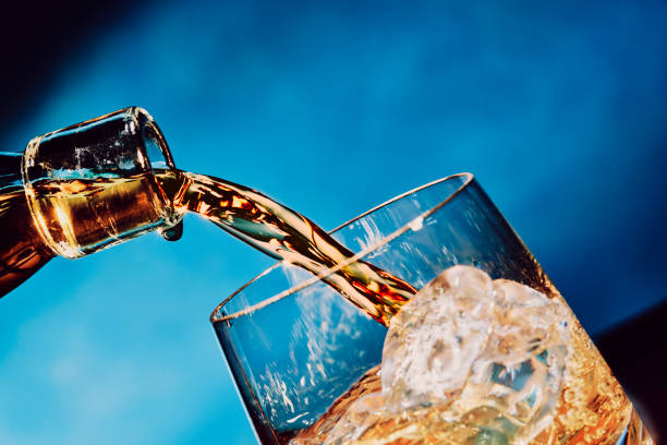 versando un bicchiere di whisky sul ghiaccio - whisky alcohol pouring glass foto e immagini stock