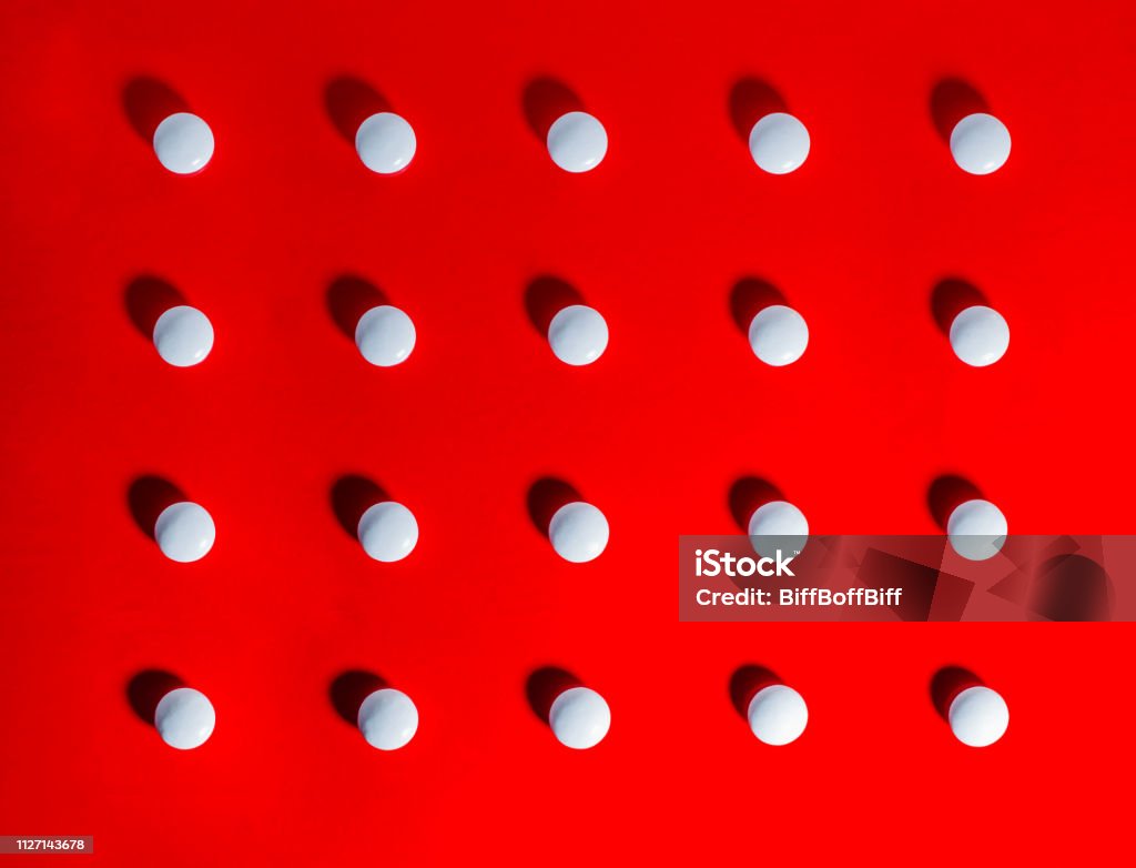 White Pills against Red Background White pills arranged in grid against bright red background Pill Stock Photo