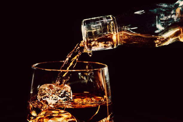 versando un bicchiere di whisky sul ghiaccio - whisky alcohol pouring glass foto e immagini stock