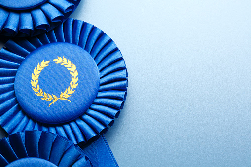 Three blue ribbons stacked upon each other on a light blue background.