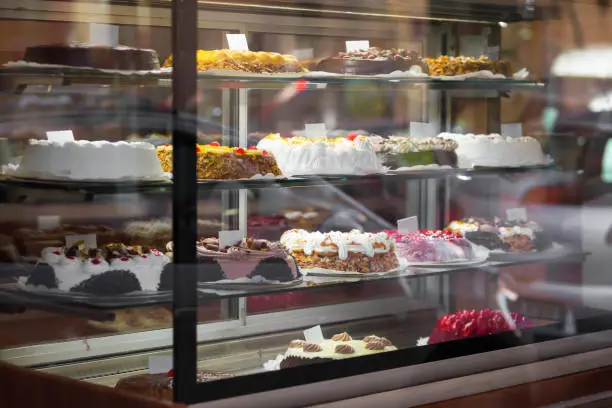 Photo of Appetizing cakes in the window of a pastry shop. Tasty sweets on the baking store shelves