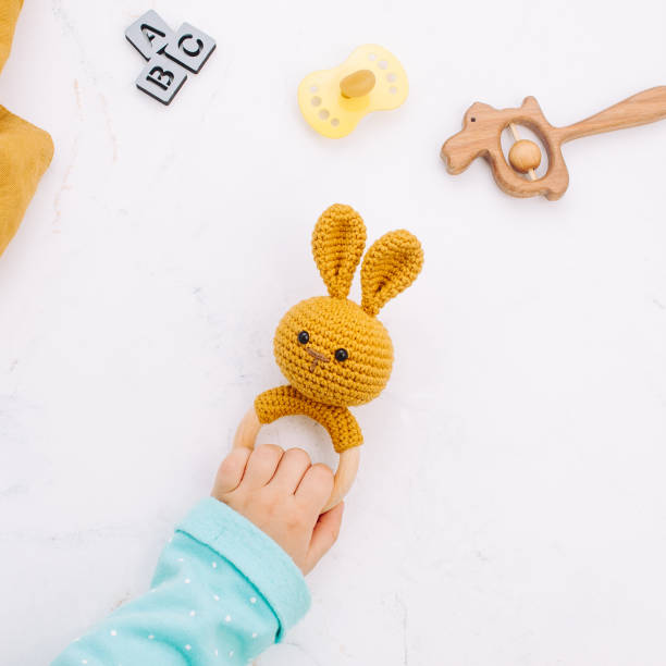 Kids hand holding bunny beanbag made from natural materials on marble background Kids hand holding bunny beanbag made from natural materials on light marble background. Top view, flat lay. baby1 stock pictures, royalty-free photos & images