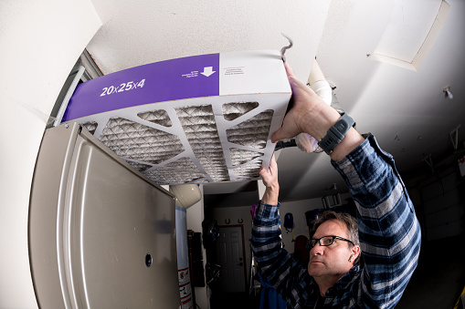 Handyman sustituye el filtro en el horno de aire caliente en un hogar photo