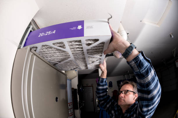 Handyman replaces the filter in the hot air furnace at a home stock photo