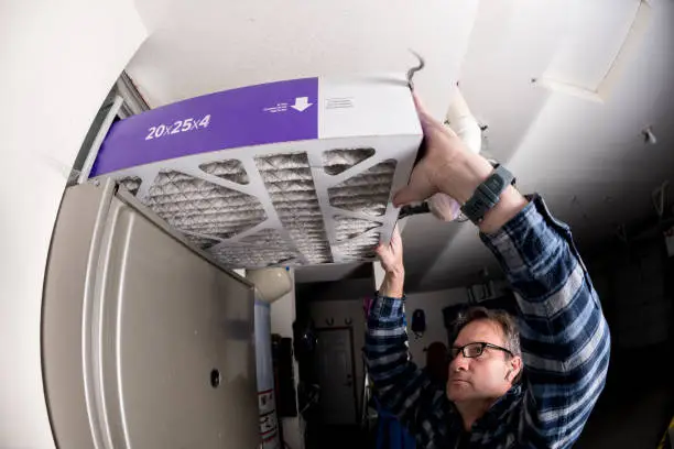 Photo of Handyman replaces the filter in the hot air furnace at a home