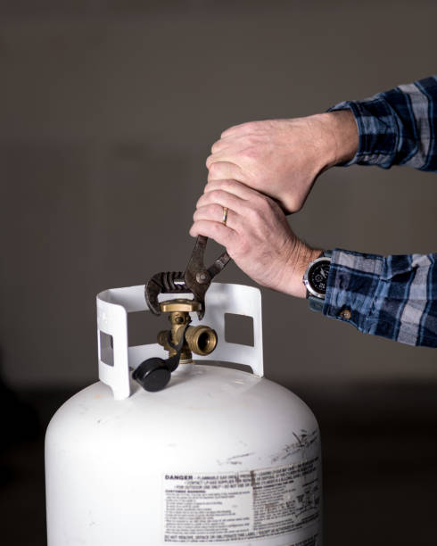 istock Using a pair of pliers to try and open a propane take with a tight valve 1127146470