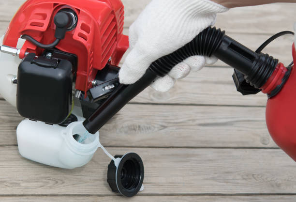 istock worker's hands pour fuel into the red lawn mower tank close up 1127147847