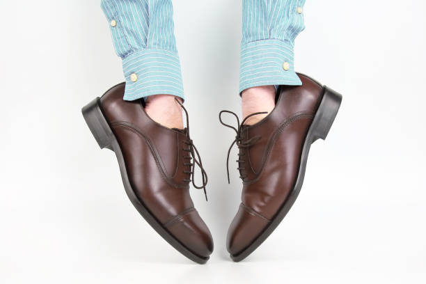 istock Classic brown shoes worn on the hands on a white background 1127147978