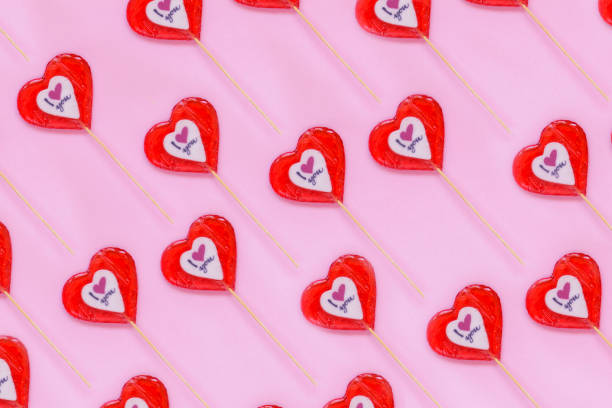 istock Red lollypop heart shape candy on stick on pink background 1127154703