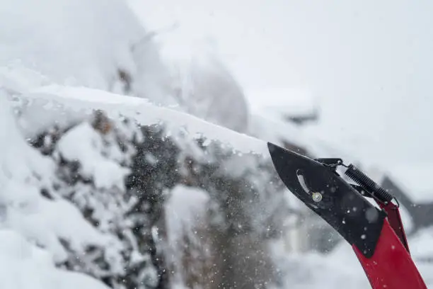 Someone uses a snowthrower outdoors in winter while it is snowing