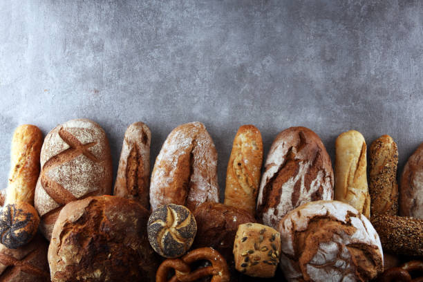 istock Assortment of baked bread and bread rolls on stone table background 1127154901