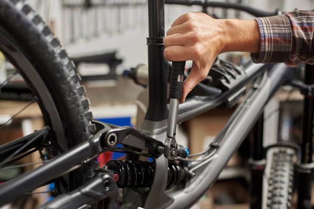 istock Male mechanic working in bicycle repair shop using tools 1127154965