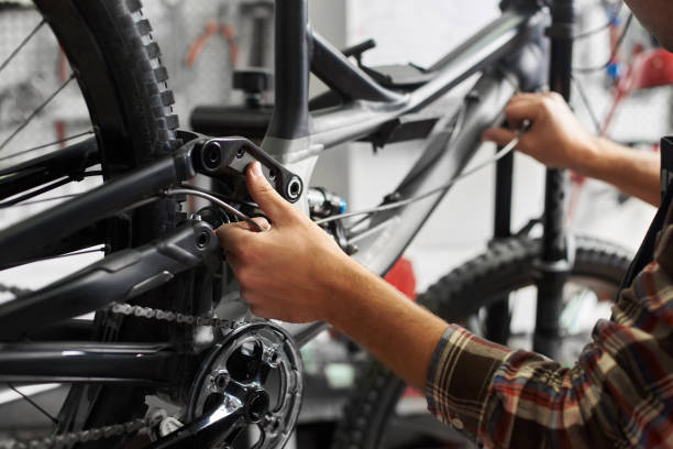 istock Male mechanic working in bicycle repair shop using tools 1127155506