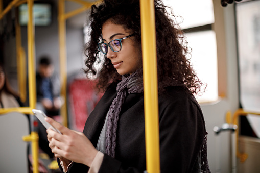 Mujer joven viajando en bus y utilizando el teléfono inteligente photo