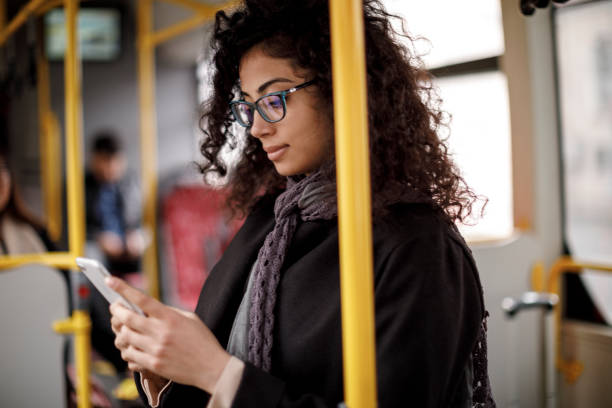 バスで旅行し、スマートフォンを使用して若い女性 - city of mobile ストックフォトと画像