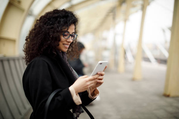 istock Smiling woman using smart phone on station 1127157623
