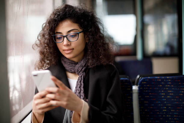 Young woman traveling by bus and using smart phone