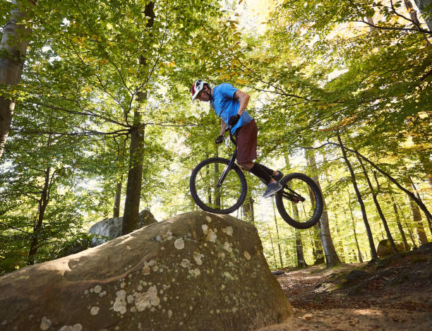 istock Cyclist balancing on front wheel on trial bicycle on boulder 1127160632