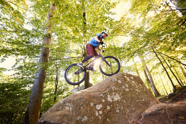 istock Cyclist balancing on front wheel on trial bicycle on boulder 1127160640
