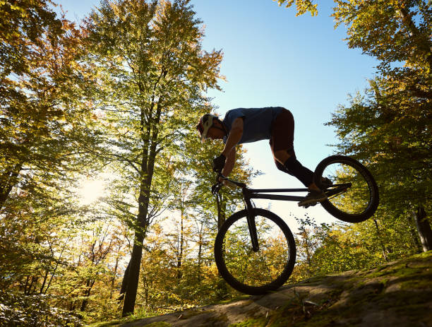 istock Cyclist balancing on front wheel on trial bicycle on boulder 1127160649