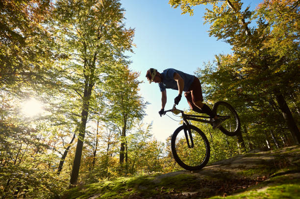 istock Cyclist balancing on front wheel on trial bicycle on boulder 1127160656