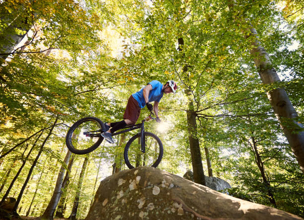 istock Cyclist balancing on front wheel on trial bicycle on boulder 1127160657