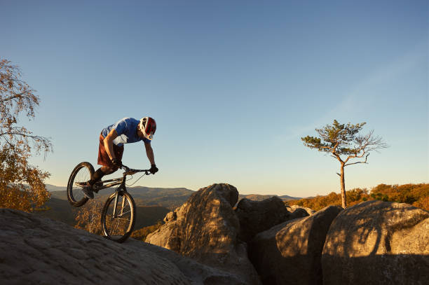 istock Cyclist balancing on front wheel on trial bicycle on boulder 1127160732
