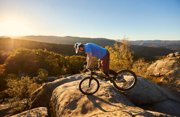 istock Cyclist balancing on front wheel on trial bicycle on boulder 1127160958