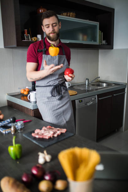 istock Man throwing pepper into air. guy preparing food at kitchen counter 1127161101