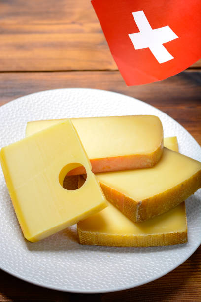 assortment of swiss cheeses emmental or emmentaler medium-hard cheese with round holes, gruyere, appenzeller and raclette used for traditional cheese fondue and gratin and flag of switzerland - cheese emmental cheese switzerland grated imagens e fotografias de stock