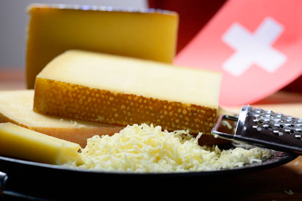 assortment of swiss cheeses emmental or emmentaler medium-hard cheese with round holes, gruyere, appenzeller and raclette used for traditional cheese fondue and gratin and flag of switzerland - cheese emmental cheese switzerland grated imagens e fotografias de stock