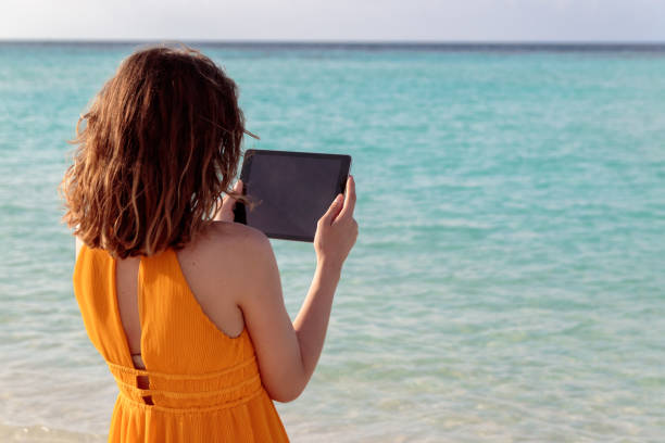 istock young woman standing in front of the sea and using her tablet during sunset 1127165996