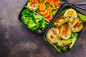 Healthy meal prep containers with green burgers, broccoli, chickpeas and salad.