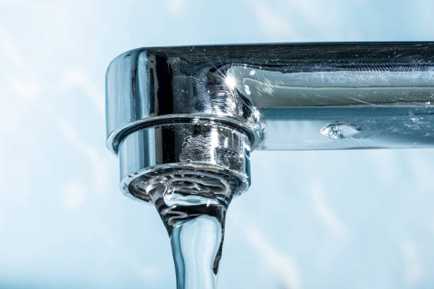 istock Water flows from a modern chromed water tap faucet macro close-up. 1127170728
