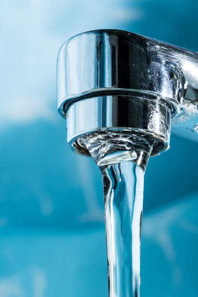 istock Water flows from a modern chromed water tap faucet macro close-up. 1127171854