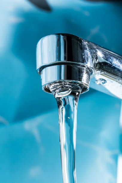 istock Water flows from a modern chromed water tap faucet macro close-up. 1127171880