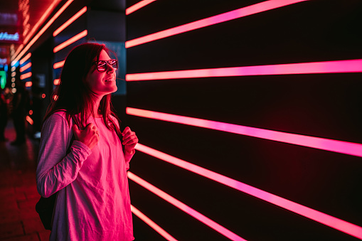 Young woman next to pink and orange neon light