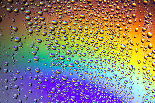 Drops of water against the background of the rainbow and with its reflection in them
