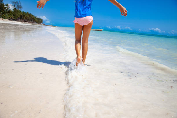 istock Little Girl walking barefoot along idyllic Tropical Beach 1127186847
