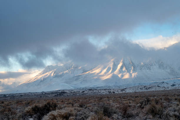 istock morning sunlight and clouds over fresh desert snowfall and snowy mountain peaks 1127189185