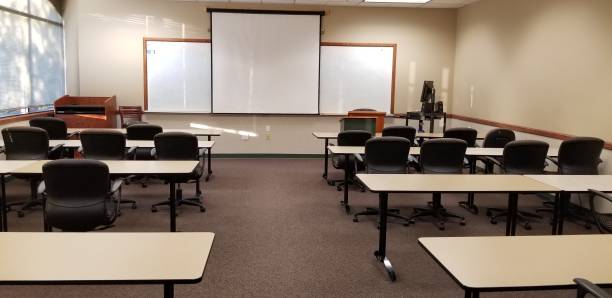 aula vacía con mesas, sillas, estrados, proyector y pantalla vista desde la parte trasera de la sala de - classroom education chair carpet fotografías e imágenes de stock