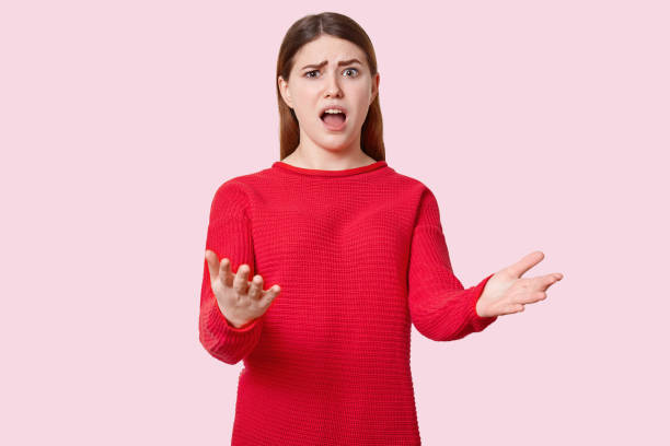 istock Indignant beautiful young woman gestures with puzzlement, opens mouth widely, raises eyebrows, dressed in red clothes, isolated over rosy studio wall. So what to do in this difficult situation? 1127190563