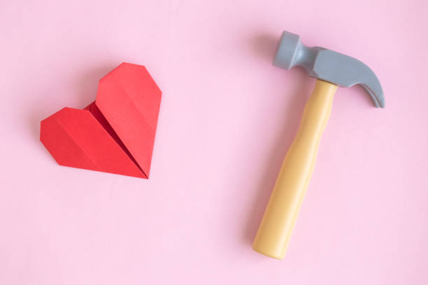 Paper heart and hammer toy on rose background abstract.