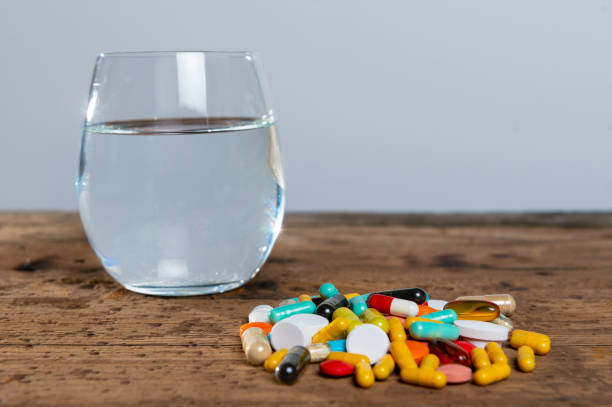 Many pills and a glass of water stock photo