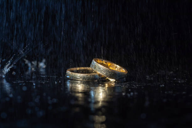 istock Wedding rings lying on dark surface shining with light close up macro. Water splashes 1127194949