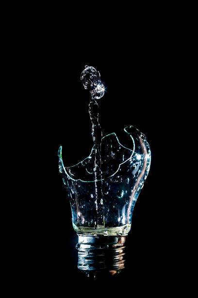 istock Creative broken light bulb with water fountain on isolated black background with flash 1127195643