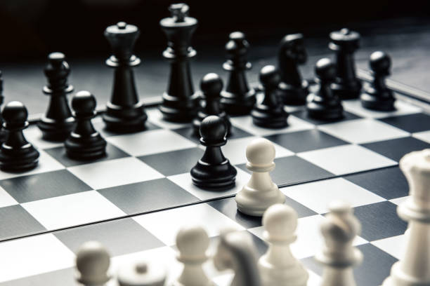 istock Chess board with black and white chess facing each other. White and black pawns go on the attack 1127201675