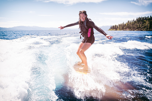 Mother wake surfs behind a boat on beautiful Lake Tahoe, California.