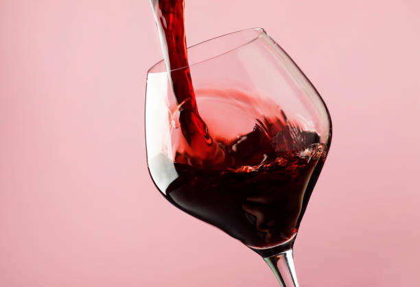 French dry red wine, pours into glass, trendy pink background French dry red wine, pours into glass, trendy pink background, space for text, selective focus maroon photos stock pictures, royalty-free photos & images