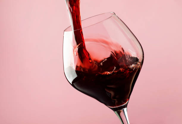 French dry red wine, pours into glass, trendy pink background French dry red wine, pours into glass, trendy pink background, space for text, selective focus maroon stock pictures, royalty-free photos & images